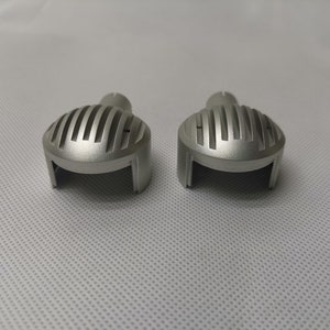 May include: Two silver metal motorcycle headlight covers with a ribbed design.