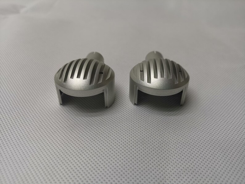 May include: Two silver metal motorcycle headlight covers with a ribbed design.