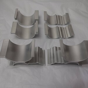 May include: Six silver metal brackets with a curved shape and a ribbed design. The brackets are arranged in two rows of three.