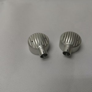 May include: Two silver metal earbud covers with a ribbed design. The covers have a small hole at the bottom.