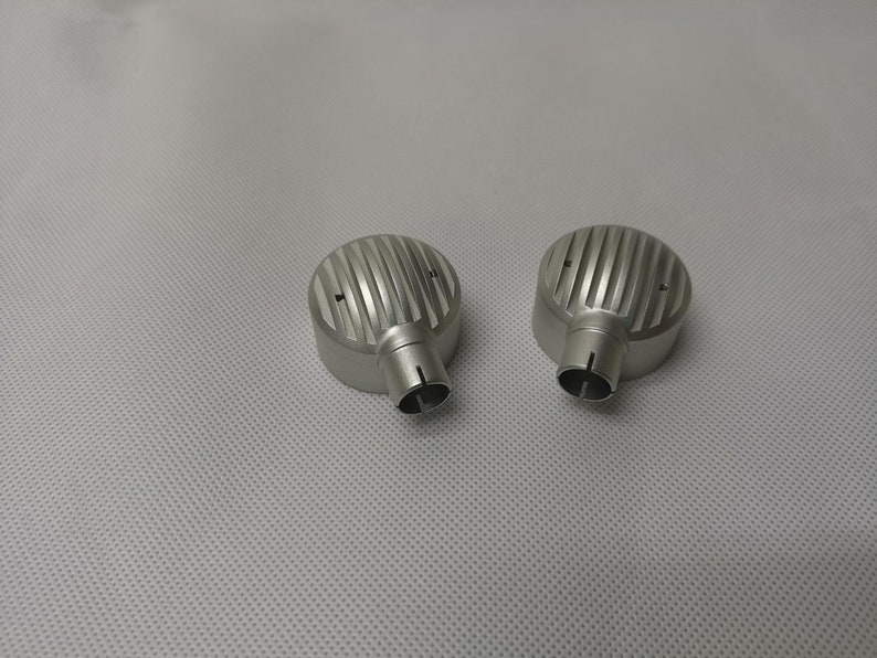 May include: Two silver metal earbud covers with a ribbed design. The covers have a small hole at the bottom.