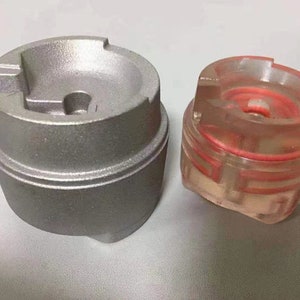 Puede incluir: Dos tapas met&aacute;licas redondas, una plateada y otra transparente con un anillo rojo en el interior. La tapa plateada tiene un peque&ntilde;o agujero en el centro.