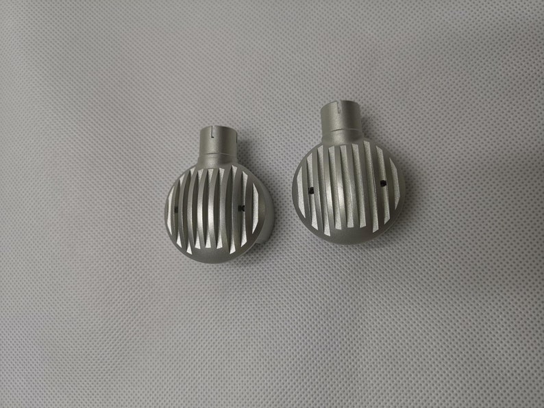 May include: Two silver metal round knobs with a grooved design. The knobs have a small hole on each side.