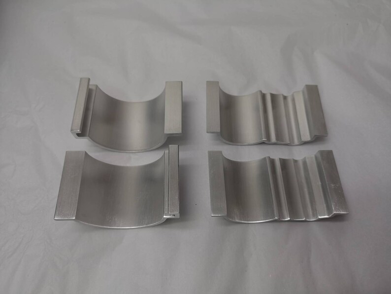 May include: Four silver metal rings, two with a smooth surface and two with a textured surface. The rings are all the same size and shape.