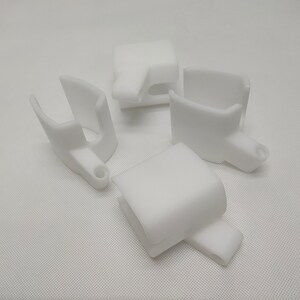 Peut inclure: Quatre pi&egrave;ces en plastique blanc imprim&eacute;es en 3D avec un design en forme de crochet. Les pi&egrave;ces sont con&ccedil;ues pour &ecirc;tre fix&eacute;es &agrave; un objet plus grand.