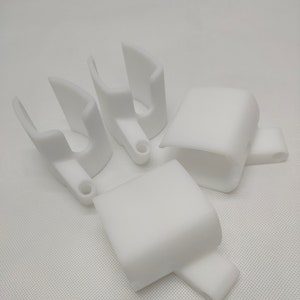 Peut inclure: Quatre supports en plastique blanc imprim&eacute;s en 3D. Deux supports sont en forme de U et deux sont rectangulaires.