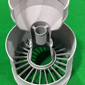 Puede incluir: Un modelo de motor a reacci&oacute;n impreso en 3D de color gris con una secci&oacute;n superior extra&iacute;ble que revela los componentes internos.