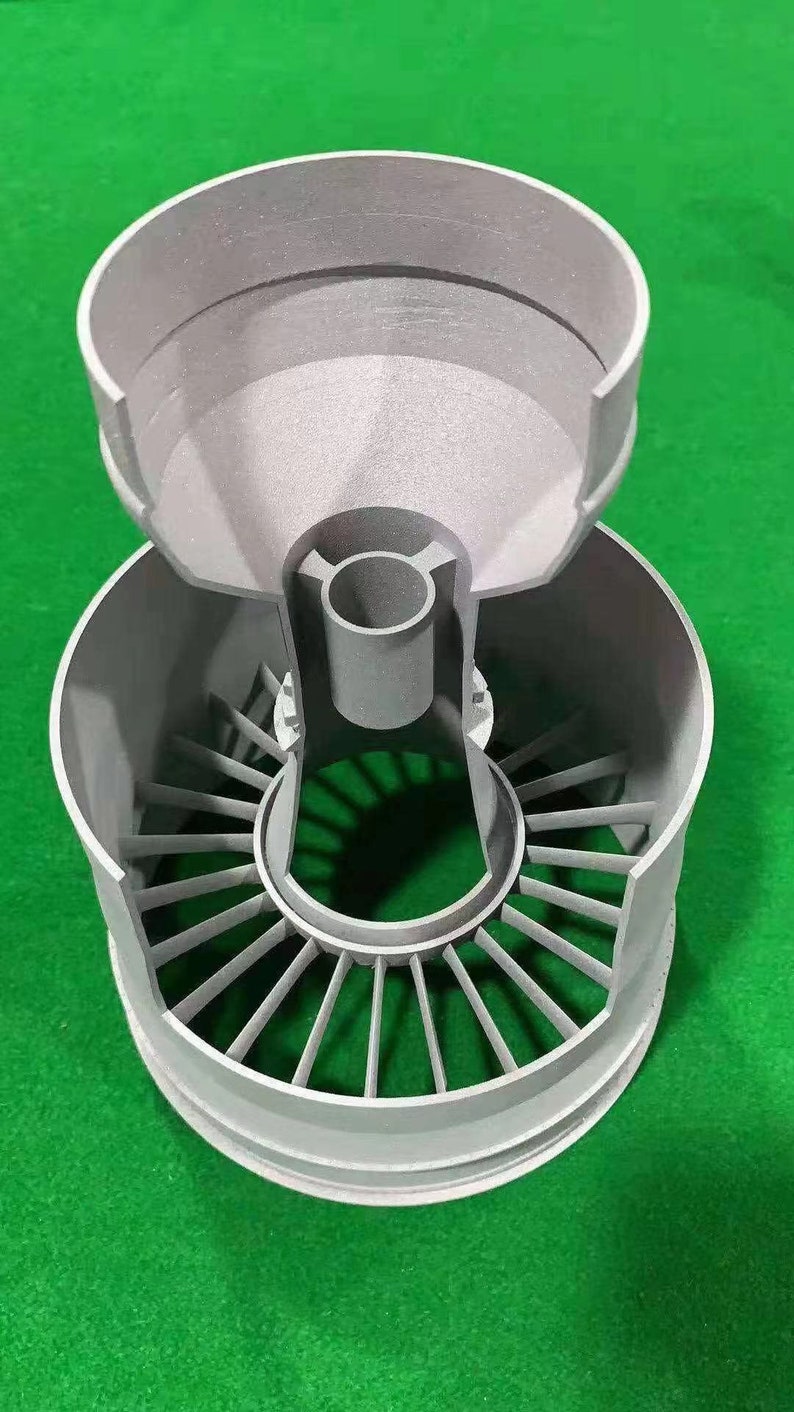 Puede incluir: Un modelo de motor a reacci&oacute;n impreso en 3D de color gris con una secci&oacute;n superior extra&iacute;ble que revela los componentes internos.