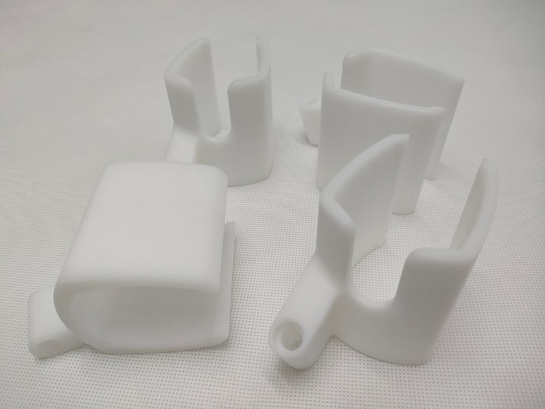 Peut inclure: Quatre supports d'angle en plastique blanc avec un bord arrondi. Les supports ont un trou d'un c&ocirc;t&eacute; et une fente de l'autre.