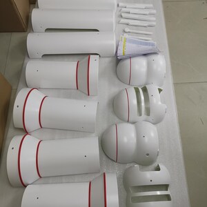 以下が含まれることがあります： 赤色のアクセントが付いた白いセラミック製の部品のセット。部品は円筒形で、さまざまな形とサイズがあります。一部の部品には中央に小さな穴があります。部品は白い表面に配置されています。
