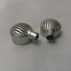 May include: Two silver metal microphone covers with a ribbed design. The covers have a small hole on the side.