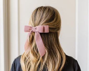 May include: A dusty rose velvet hair bow with a large bow and long tails.