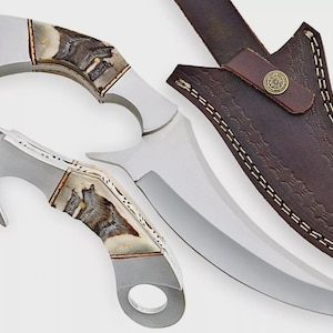 May include: Two stainless steel knives with curved blades and decorative handles featuring a wolf design. A brown leather sheath with a decorative pattern and a snap closure is also included.