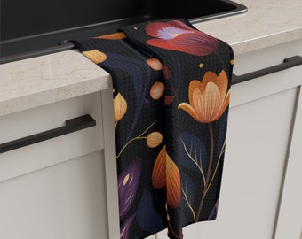 May include: A black kitchen towel with a floral pattern featuring orange, yellow, and purple flowers on a dark blue background.
