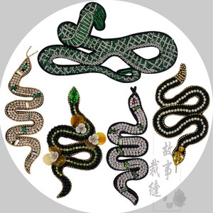 May include: Six decorative snake patches with detailed beadwork. The patches feature green, gold, black, and silver beads, with some incorporating gemstones and floral embellishments. The snakes are designed with diverse patterns and textures, suitable for embellishing clothing.