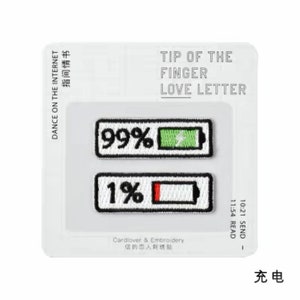 May include: Two embroidered iron-on patches depicting a battery icon with a percentage indicator. The top patch shows a green battery at 99% and the bottom patch shows a red battery at 1%. The patches are on a white background with the text "Dance on the Internet" and "Tip of the Finger Love Letter" in black.