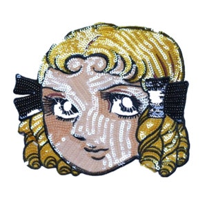May include: A sequined mask with a cartoon-style face, featuring large eyes, a small nose, and a closed mouth. The mask has blonde hair and black bows on the sides.