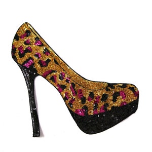 May include: A black high-heeled shoe with a gold and pink leopard print design made of sequins.