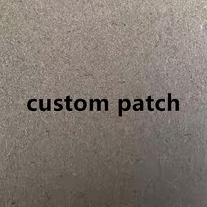 May include: A close-up of a gray, textured surface with the words "custom patch" printed in black.