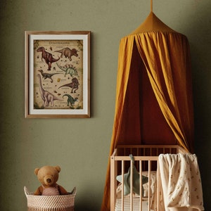K&ouml;nnte beinhalten: Ein gerahmtes Vintage-Poster mit Illustrationen verschiedener Dinosaurier, betitelt "Dinosaurs". Das Poster h&auml;ngt an einer gr&uuml;nen Wand &uuml;ber einem Holzbettchen mit einem gelben Baldachin. Ein Teddyb&auml;r sitzt in einem geflochtenen Korb.