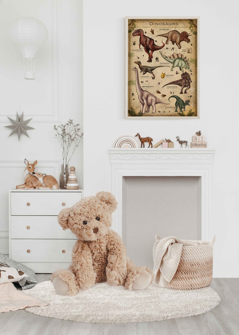 K&ouml;nnte beinhalten: Ein hellbrauner Teddyb&auml;r sitzt auf einem wei&szlig;en, flauschigen Teppich in einem Kinderzimmer. Hinter dem B&auml;ren h&auml;ngt ein gerahmtes Poster mit dem Wort "Dinosaurs" an der Wand. Auf einem wei&szlig;en Kaminsims stehen Holzkl&ouml;tze mit den Worten "43 Weeks".