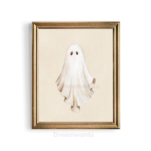 May include: A framed watercolor painting of a white ghost with two black eyes. The ghost is depicted in a simple, whimsical style, with a flowing, translucent form. The background is a light beige color, and the frame is a simple gold color.