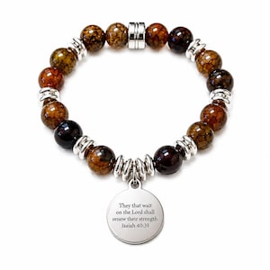 Peut inclure: Un bracelet composé de perles rondes en agate craquelée marron, alternées avec des entretoises en métal argenté. Une breloque ronde en métal argenté est suspendue au bracelet, gravée du texte : They that wait on the Lord shall renew their strength. Isaiah 40:31.
