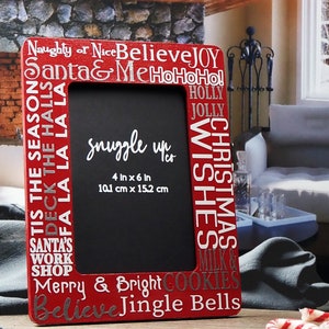 May include: Red picture frame with a black background and white text. The text on the frame says "Naughty or Nice Believe JOY Santa & Me HoHoHo! Tis the Season Deck the Halls Fa La La La La Santa's Work Shop Merry & Bright Cookies Believe Jingle Bells" and "Christmas Wishes Holly Jolly Milk &"  The frame is 4 inches by 6 inches or 10.1 centimeters by 15.2 centimeters.