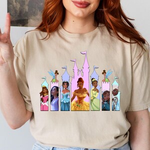 a woman wearing a t - shirt with a picture of princesses on it