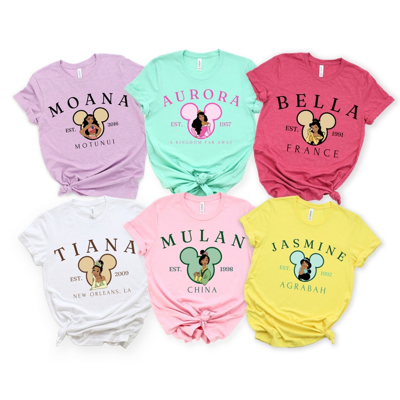 以下が含まれることがあります： 6枚の異なる色のTシャツに、それぞれディズニーのプリンセスキャラクターが描かれています。Tシャツはすべて半袖で、クルーネックです。登場するプリンセスは、モアナ、オーロラ、ベル、ティアナ、ムーラン、ジャスミンです。各Tシャツには、プリンセスの名前、紹介された年、出身地が書かれています。