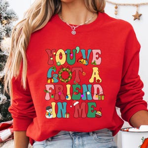 a woman wearing a red sweatshirt that says you've got a friend in me