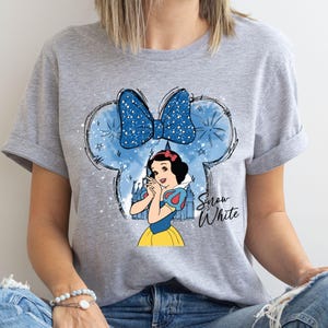 a woman wearing a gray shirt with snow white on it