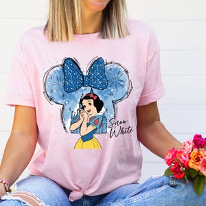 a woman wearing a pink shirt with snow white on it