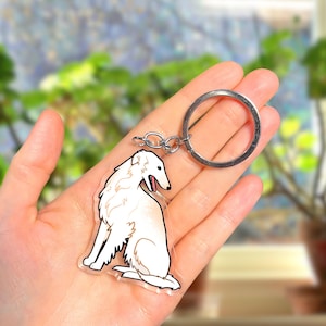 May include: White Borzoi dog keyring with a silver key ring. The dog is sitting with its tongue sticking out.