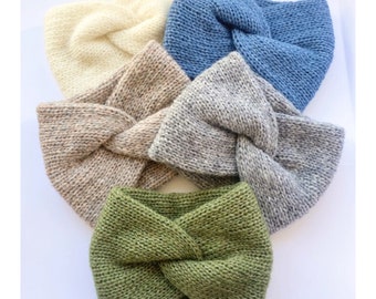 May include: Five knitted headbands in different colours: beige, grey, blue, green, and cream. The headbands are twisted and have a knot in the centre.