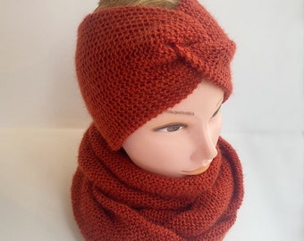 May include: A rust-coloured knitted headband and infinity scarf set. The headband has a twisted knot design. The scarf is a wide, circular loop. The set is displayed on a mannequin head.