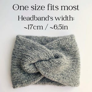 May include: A grey knitted headband with a twisted knot design. The text on the image reads: "One size fits most. Headband's width: ~17cm". This warm accessory is ideal for keeping ears warm.