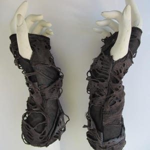 May include: A pair of black fingerless gloves with a distressed, ripped look. The gloves are made of a soft, stretchy fabric and have a unique, edgy style.