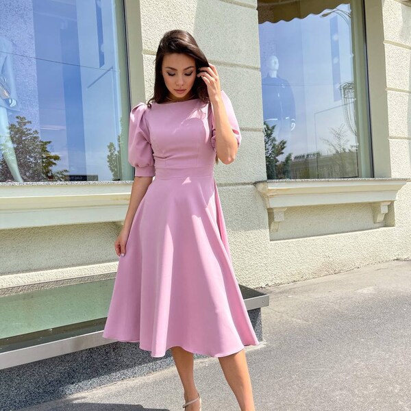 Elegante vestido midi con mangas abullonadas en color rosa pastel, perfecto para invitadas a una boda o fiesta de graduación con silueta entallada y acampanada