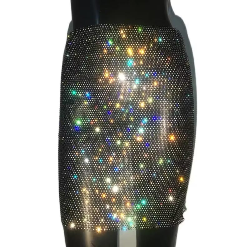 May include: A short black skirt with a sparkly iridescent design. The skirt is made of a mesh fabric with small rhinestones.