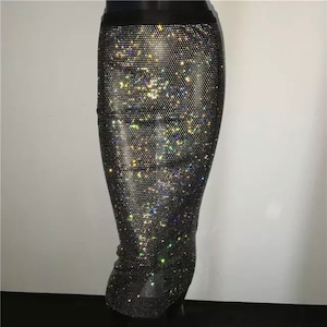 May include: A black skirt covered in iridescent rhinestones. The skirt is fitted and has a high waist.