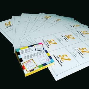 Op de afbeelding: Een set van 52 koppeluitdagingen, gedrukt op witte kaarten met blauwe randen. De kaarten zijn in een rasterpatroon gerangschikt en bevatten een gouden nummer 52 en de tekst "Couple Challenges". De kaarten maken deel uit van een spel dat is ontworpen om koppels te helpen elkaar te verbinden en plezier te hebben samen.