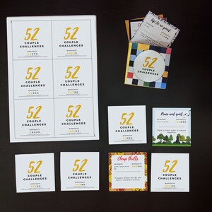 Op de afbeelding: Een set van 52 kaarten met uitdagingen voor koppels met verschillende thema's, waaronder "Geen onzin", "Vrede en stilte" en "Goedkope sensaties". De kaarten zijn gedrukt op wit karton met gele en zwarte tekst. De kaarten zijn gerangschikt in een raster op een zwart oppervlak.