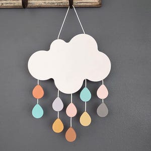 May include: A white wooden cloud with colourful raindrops hanging from it. The raindrops are in shades of pink, orange, blue, and grey.