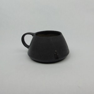 May include: A black ceramic mug with a wide, flared base and a rounded handle.