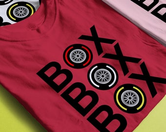 May include: Four t-shirts with the word "Boxx" and tire tread designs in black, white, yellow, and red. The shirts are in different colors: blue, white, pink, and red.