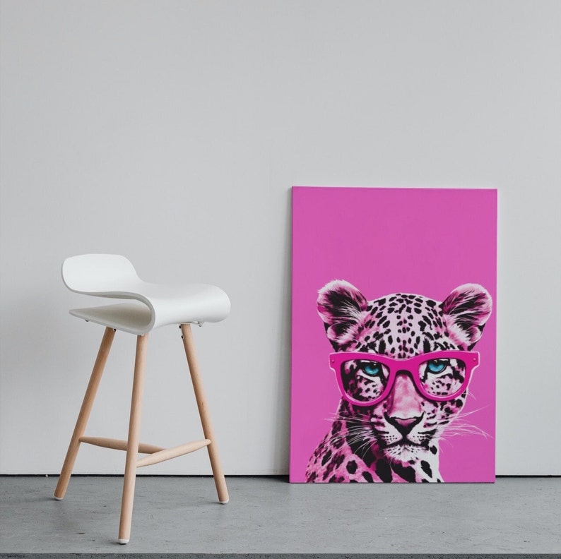 K&ouml;nnte beinhalten: Ein rosa Leinwanddruck mit einem Leoparden, der eine rosa Brille tr&auml;gt. Der Leopard schaut direkt auf den Betrachter. Der Hintergrund ist einfarbig rosa.