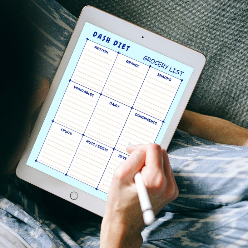 May include: A digital tablet displaying a grocery list template for the DASH diet. The template is divided into categories such as protein, grains, vegetables, dairy, condiments, fruits, nuts/seeds, and beverages.