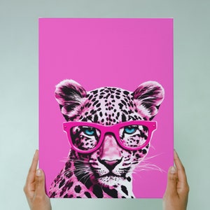 K&ouml;nnte beinhalten: Eine Illustration eines Leoparden mit rosa und schwarzem Leopardenmuster, der eine rosa Brille auf einem rosa Hintergrund tr&auml;gt.