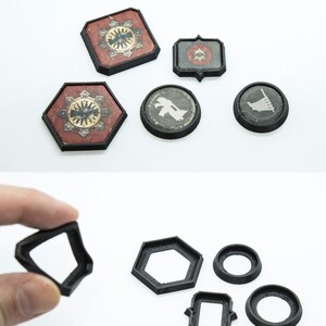 May include: Set of six black plastic game pieces, including a square, hexagon, circle, and two rectangles. The pieces are designed to be used as bases for miniature figures in a tabletop game.